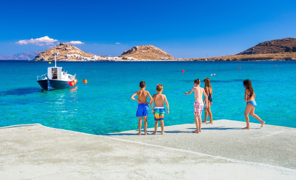 Group of kids preparing to jump into the sea from the pier at Kalafati Beach on Mykonos in Greece