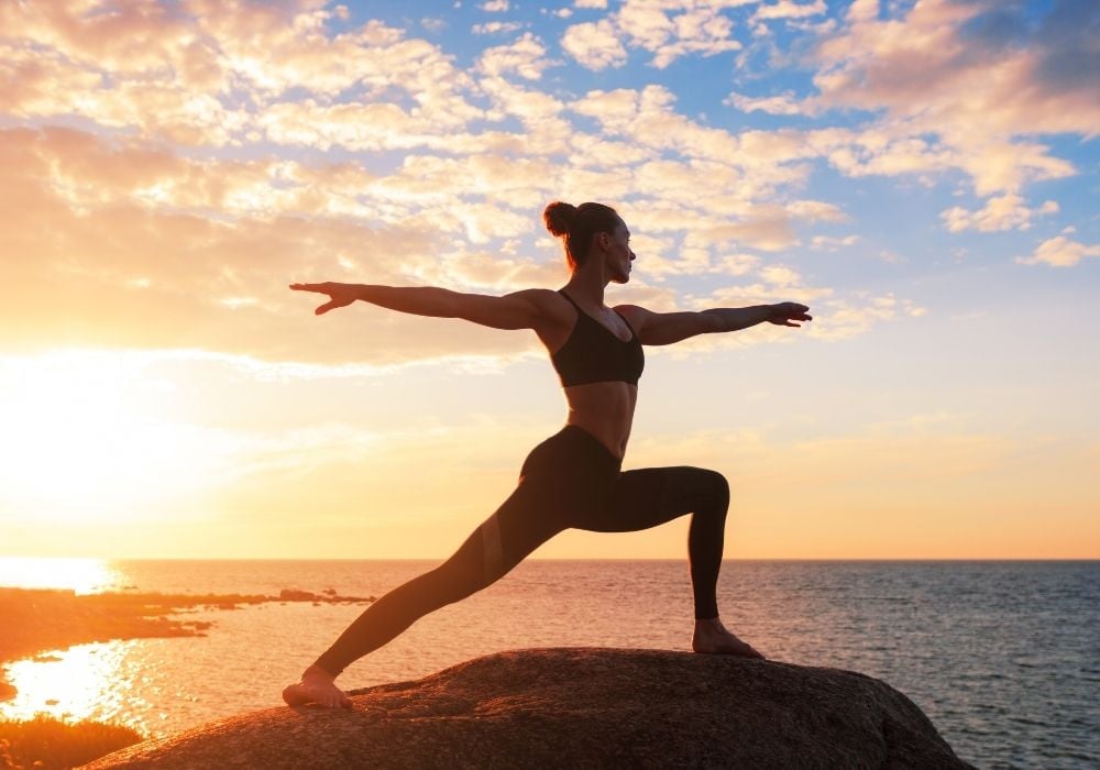 Yoga instructor next to the sea at sunset