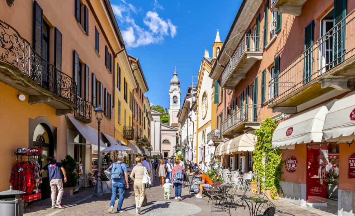 People exploring a narrow street in a colorful city in beautiful, sunny Italy