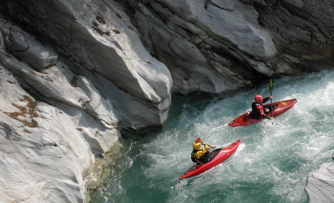 Two kayakers in rushing water in Valsesia, Piedmont, Italy