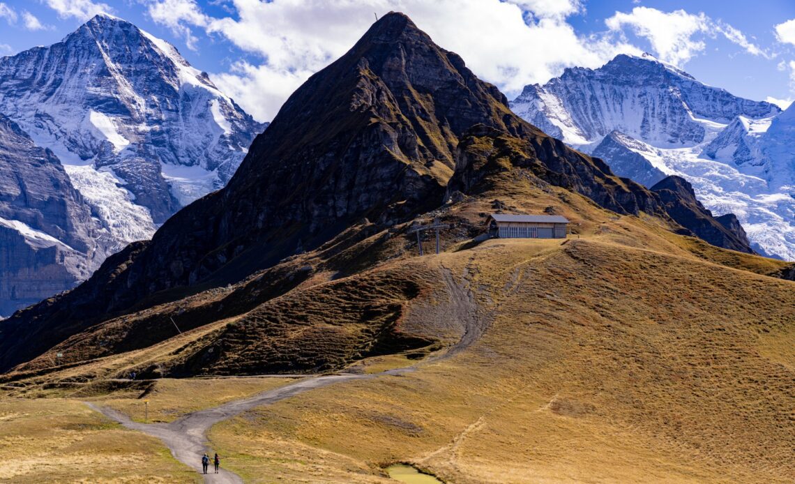 Two hikers walk along the Gemmi Pass up to a high mountain in the the Jungfrau region, Switzerland