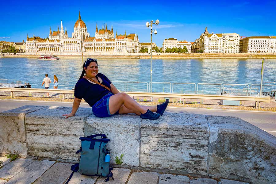 Wandrd Backpack Review - Photo of me with the Parliament of Budapest in the Background and my Wandrd Prvke Backpack on the Ground