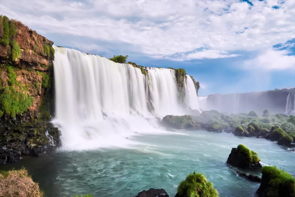 Iguazu waterfalls in Argentina, view from Devil's Mouth. Panoramic view of many majestic powerful water cascades with mist. Side view of the wide powerful waterfall.