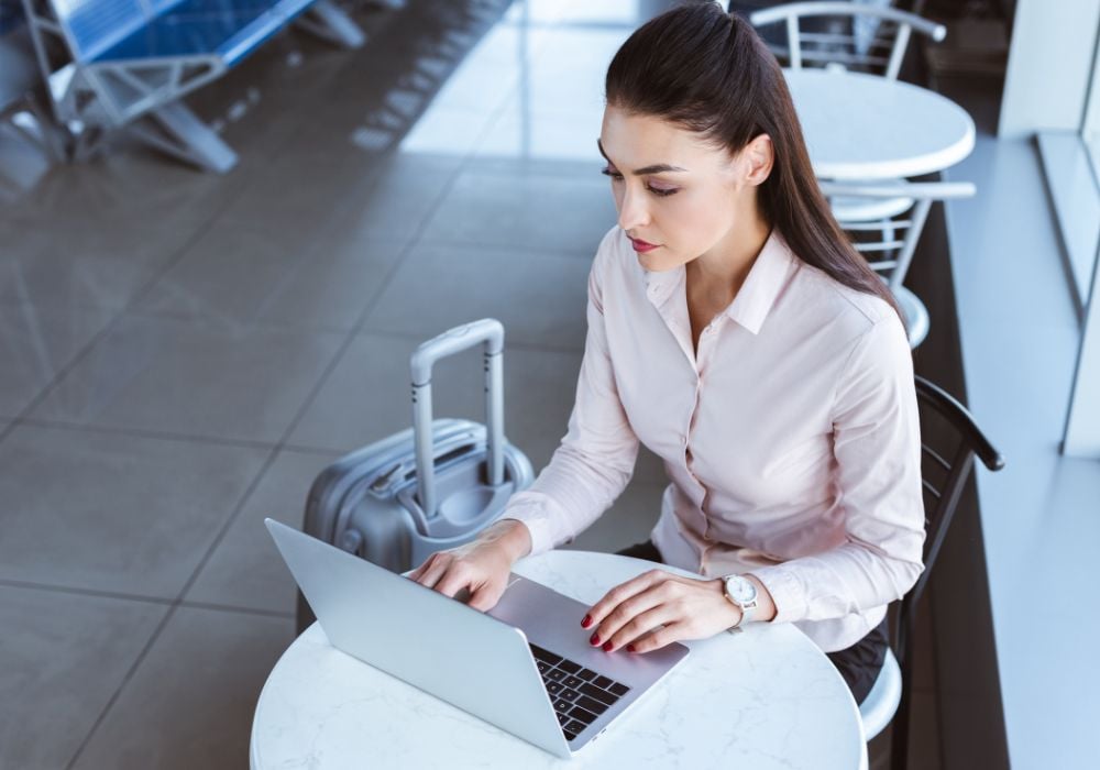 young digital nomad with luggage using laptop at the airport