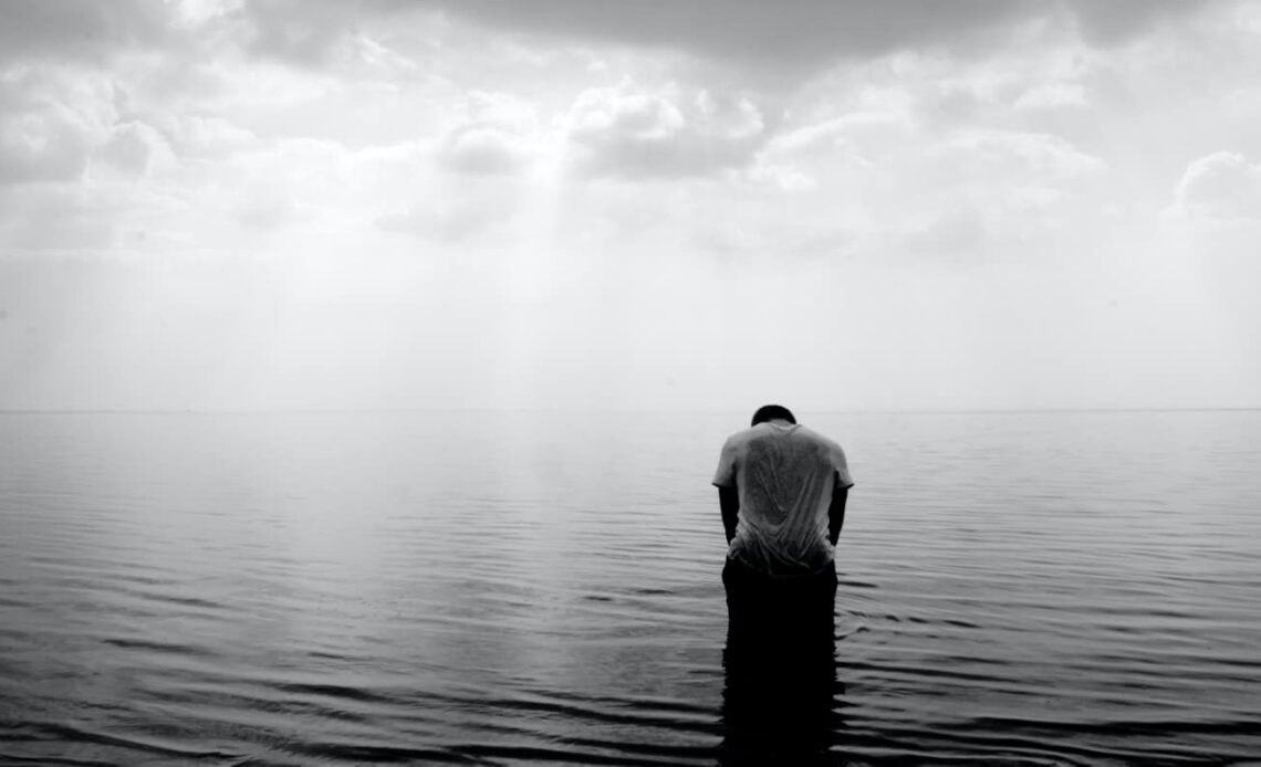 A black and white photo of a lone traveler alone in the water