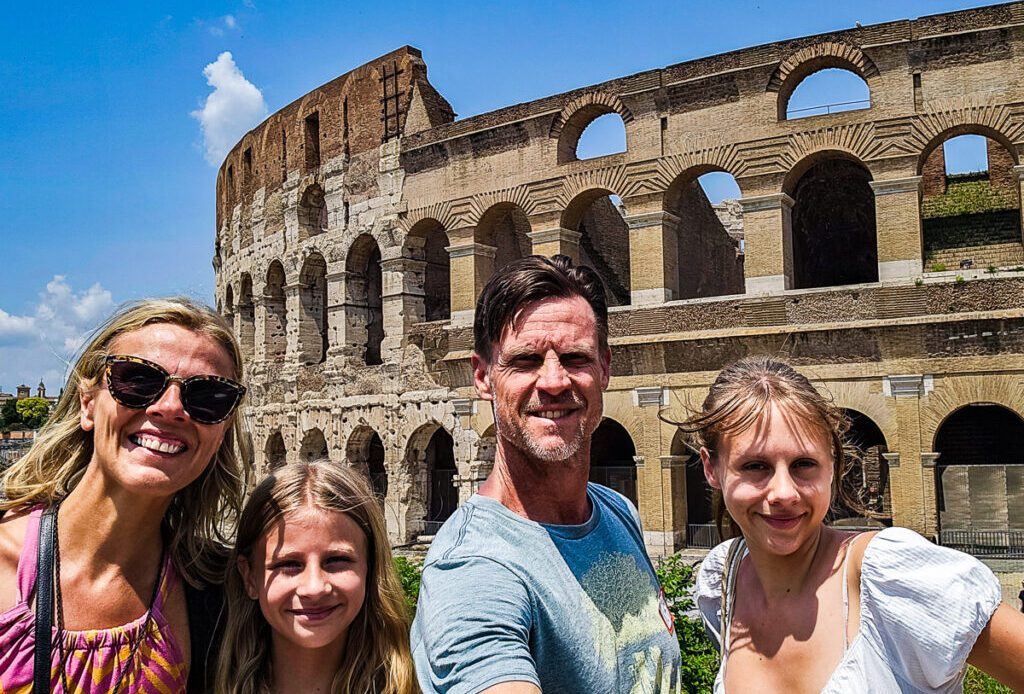 Family of four posing for a photo in front of the Colosseum in Rome