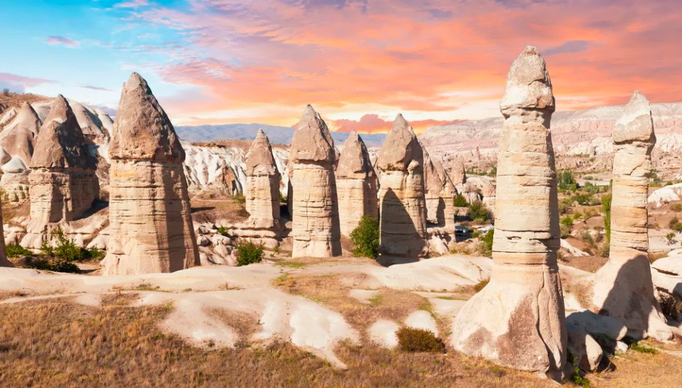 Fairy chimney rocks are dramatically lit by a sunset in Cappadocia, Turkey