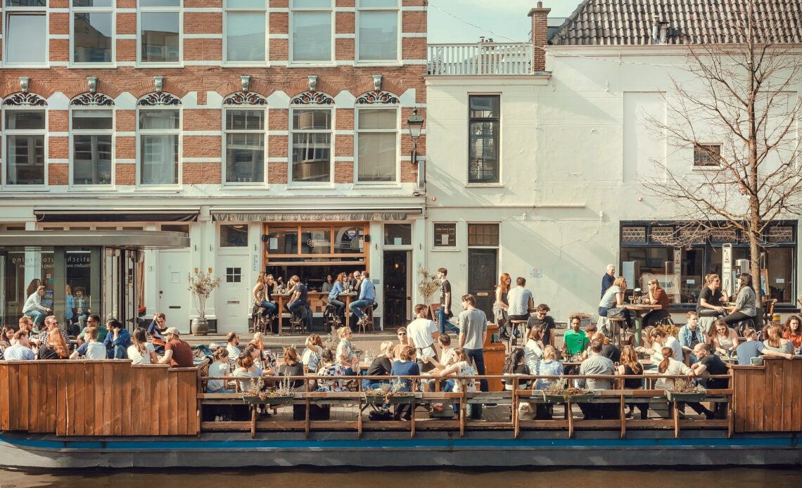 People eating and talking on riverboat cafe on the Amsterdam canal, the Netherlands