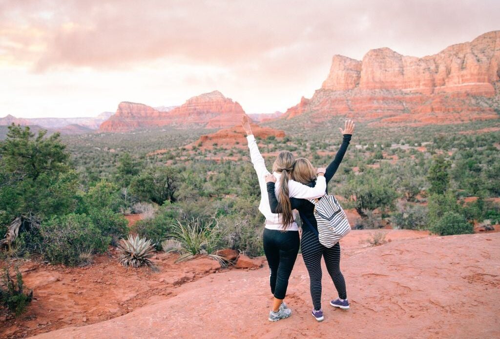 two women with their hands in the air in sedona arizona at sunset