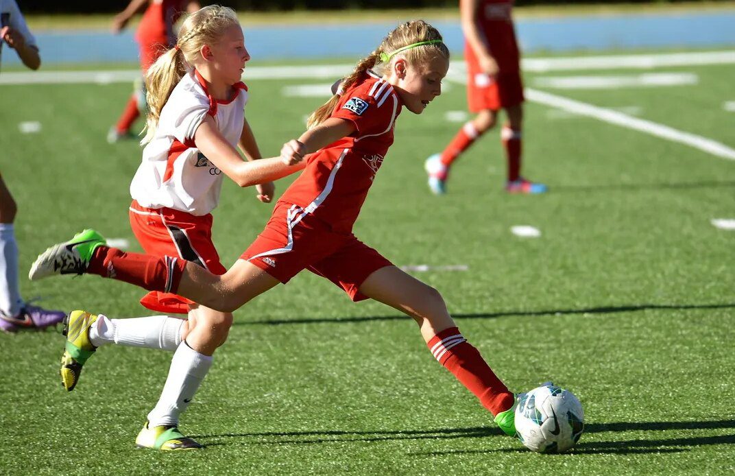 two opposing soccer players battle for the ball