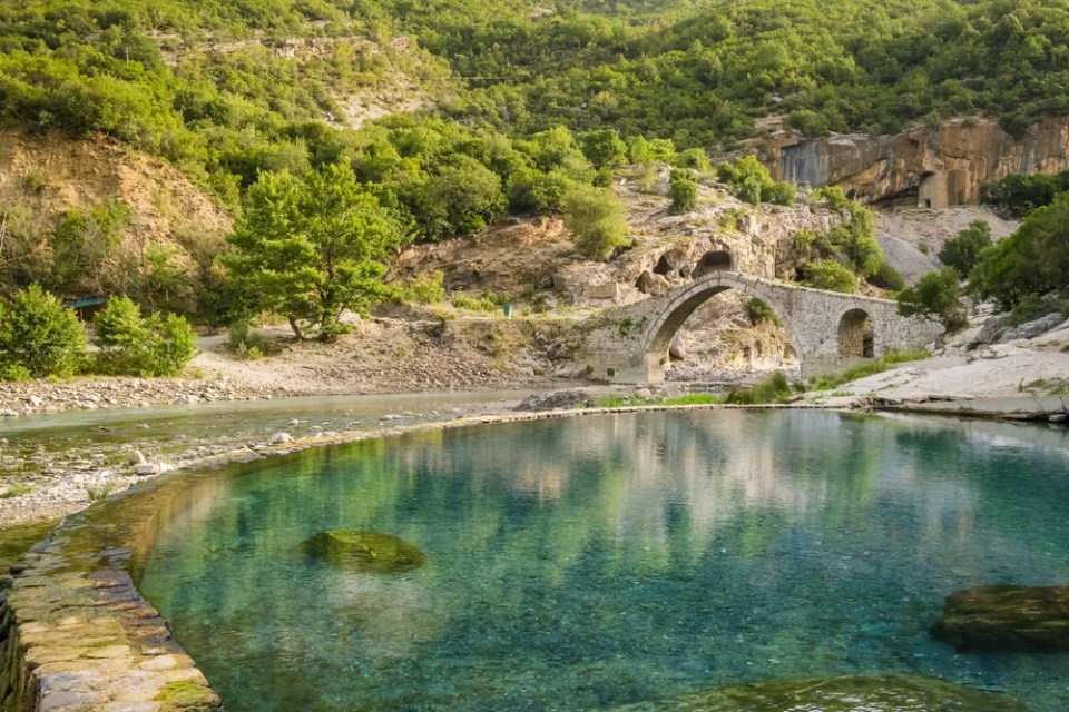 Benja Thermal Baths in Permet, Albania. Pool with hot water and old arch shape stone bridge at background. Popular tourist destination in Albania