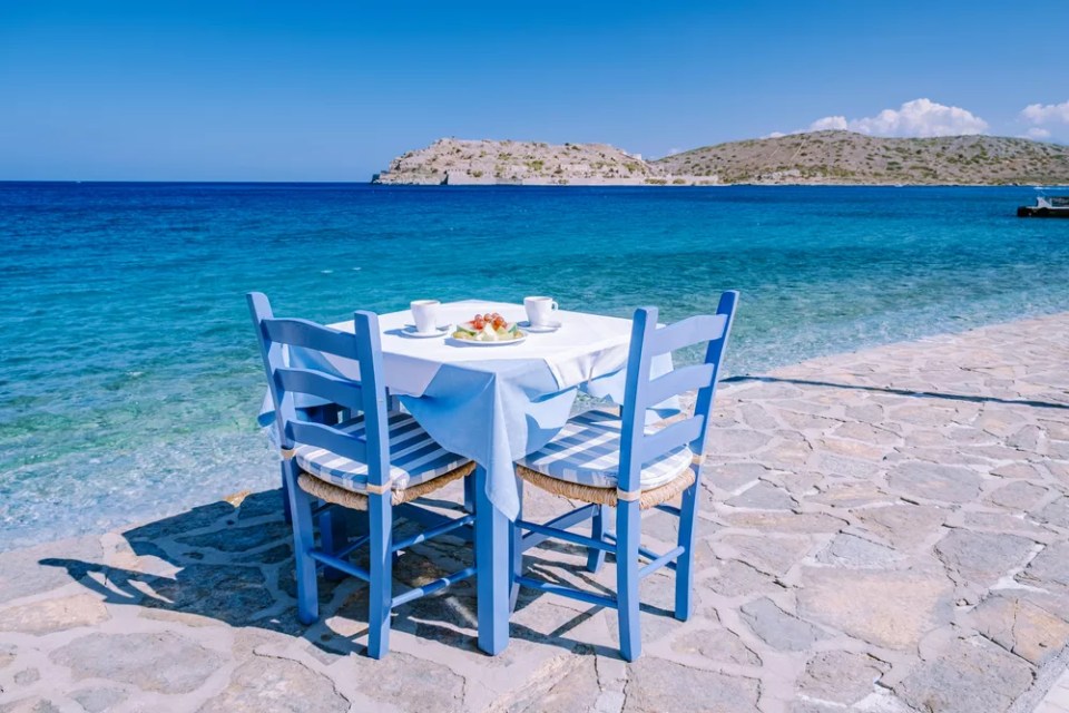 Crete Greece Plaka Lassithi with is traditional blue table and chairs and the beach in Crete Greece. Paralia Plakas, Plaka village Crete