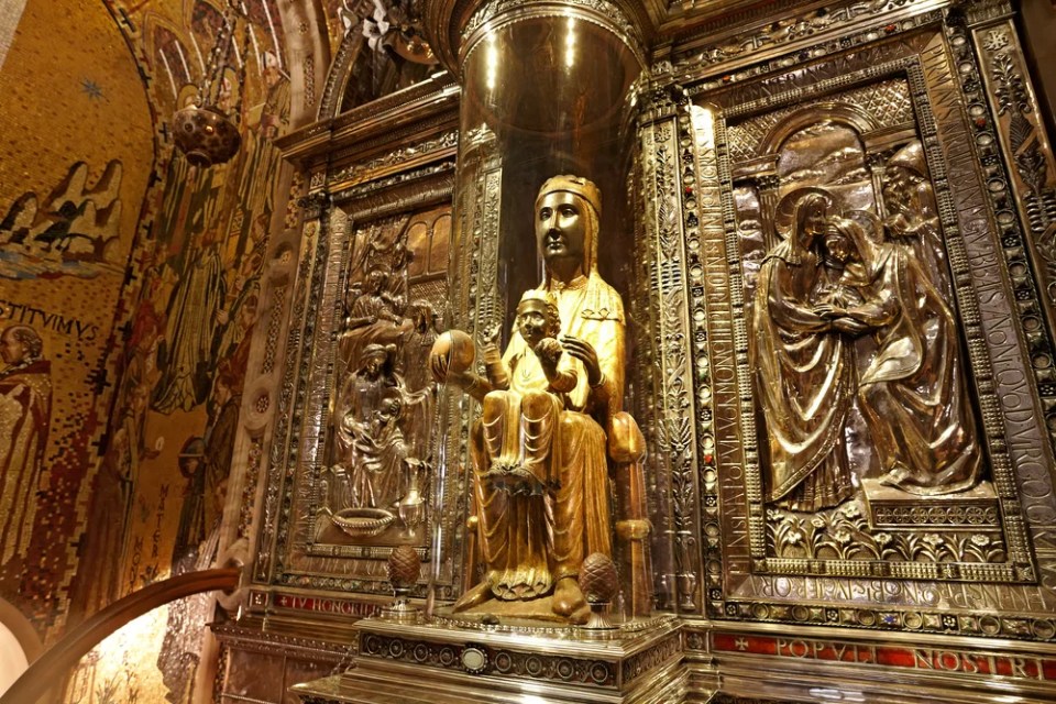 12th century statue of Black Madonna of Montserrat"La Moreneta" in cathedral of Montserrat Monastery. She is protected  glass  cover with orb protruding for pilgrims to touch. Barcelona Province Catalonia Spain