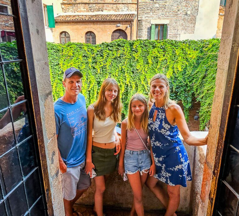 Family of four standing on Juliet's balcony in Verona