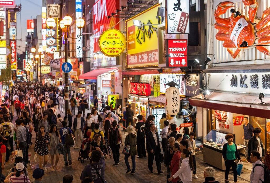 people walking the busy streets of osaka in japan with bright lights