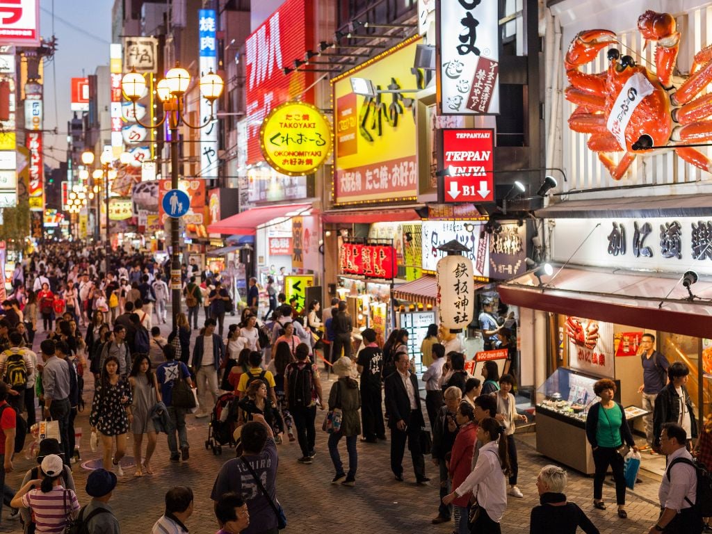 people walking the busy streets of osaka in japan with bright lights
