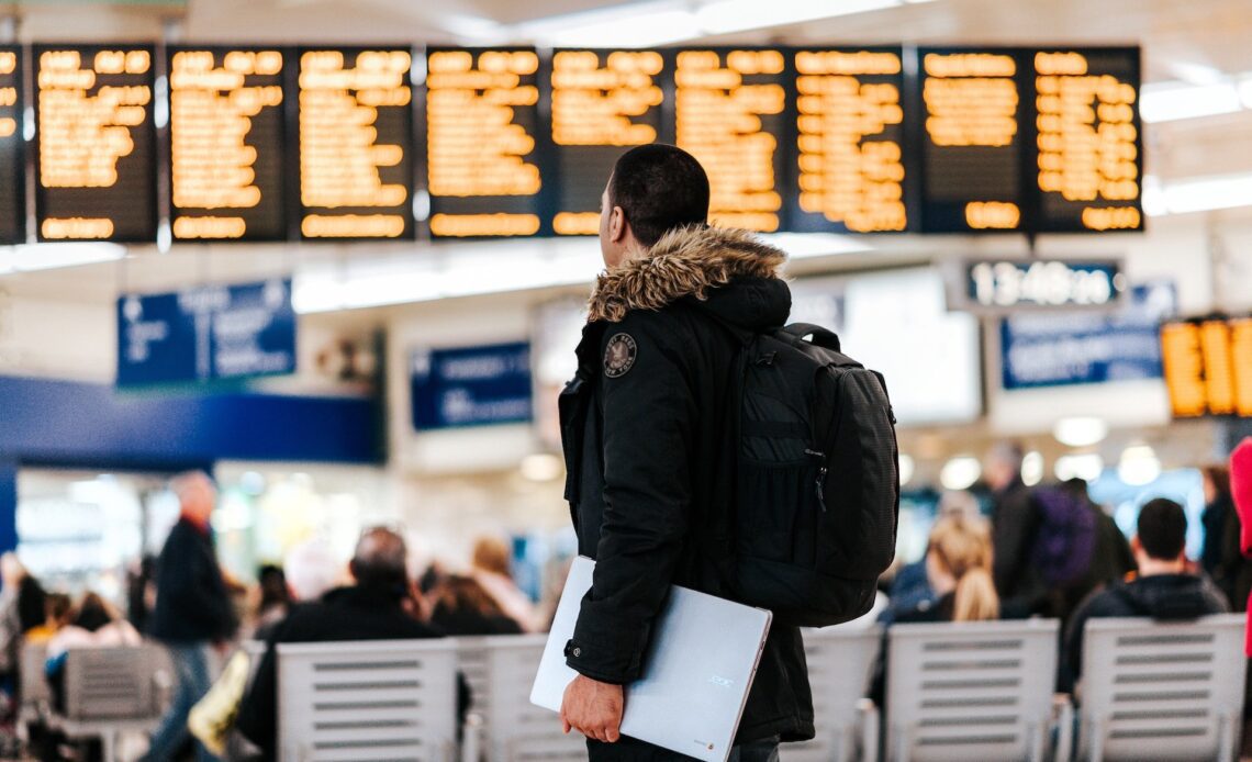 Man with laptop at an airport, where he should consider using a free VPN for travel (photo: Anete Lusina)