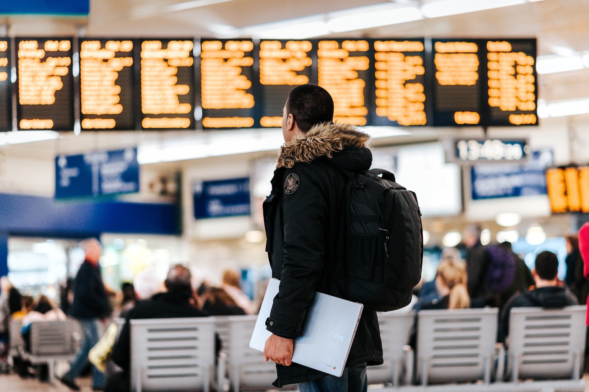 Man with laptop at an airport, where he should consider using a free VPN for travel (photo: Anete Lusina)