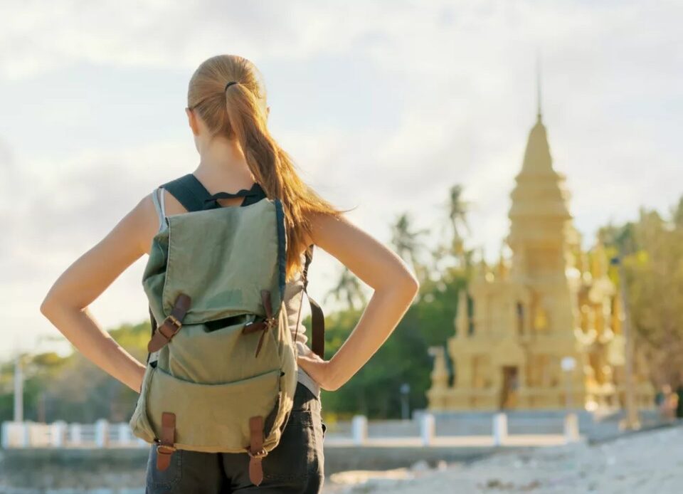 Young woman looking at golden pagoda. Hiking at Asia.