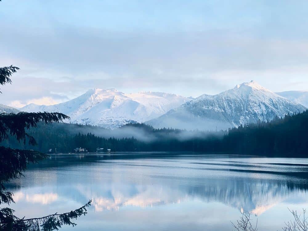 snow covered mountains beside a lake