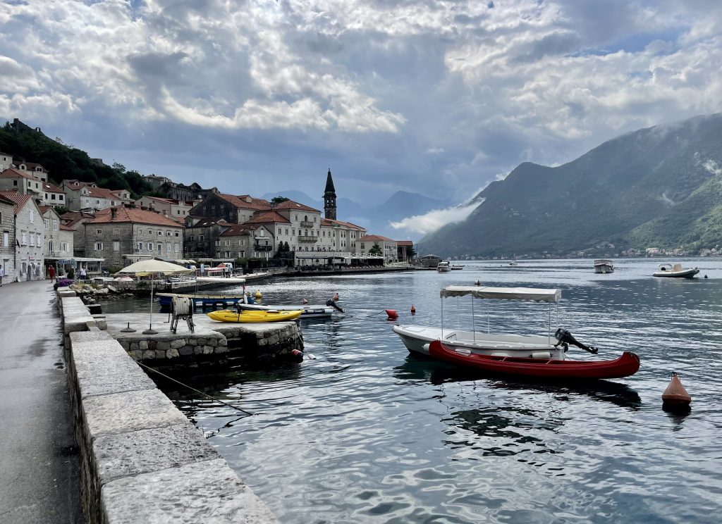 Perast, a small town on the Adriatic with lots of boats in the bay and a tiny church steeple sticking up.