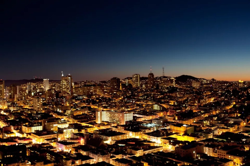 A view of a city at night with a sunset on the horizon - San Jose