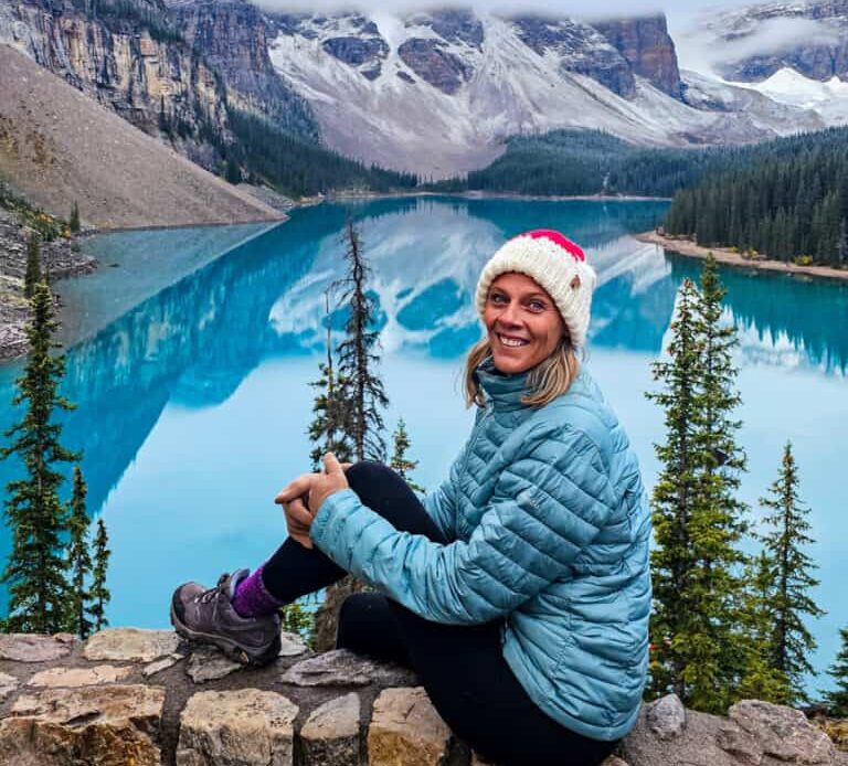 caz sitting on rock wall smiling in front of moraine  lake canada