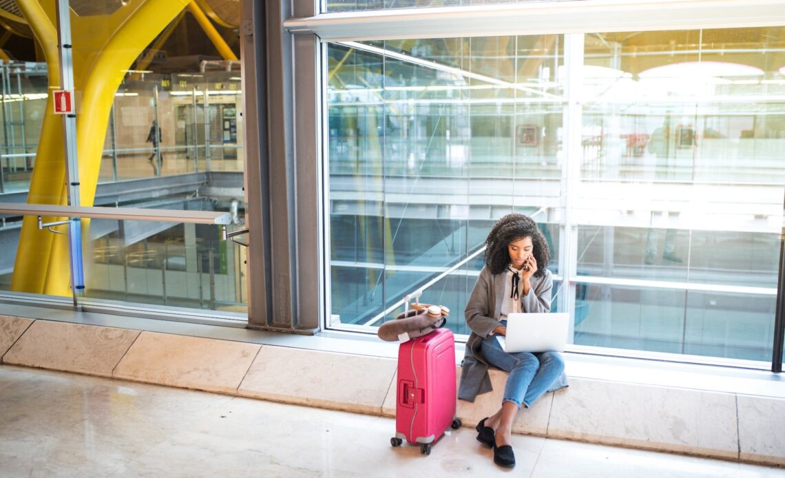 A woman working remotely at an airport (photo: Getty Images via Unsplash+ license)