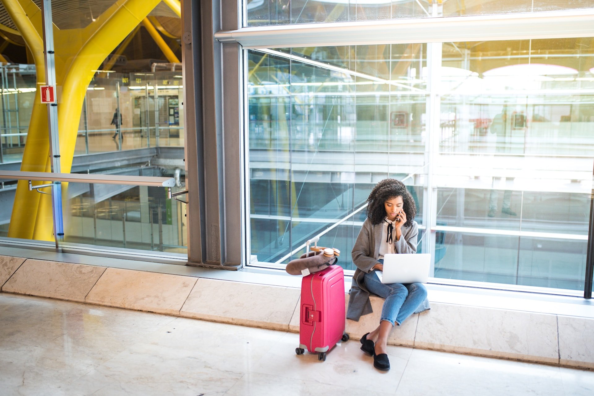 A woman working remotely at an airport (photo: Getty Images via Unsplash+ license)