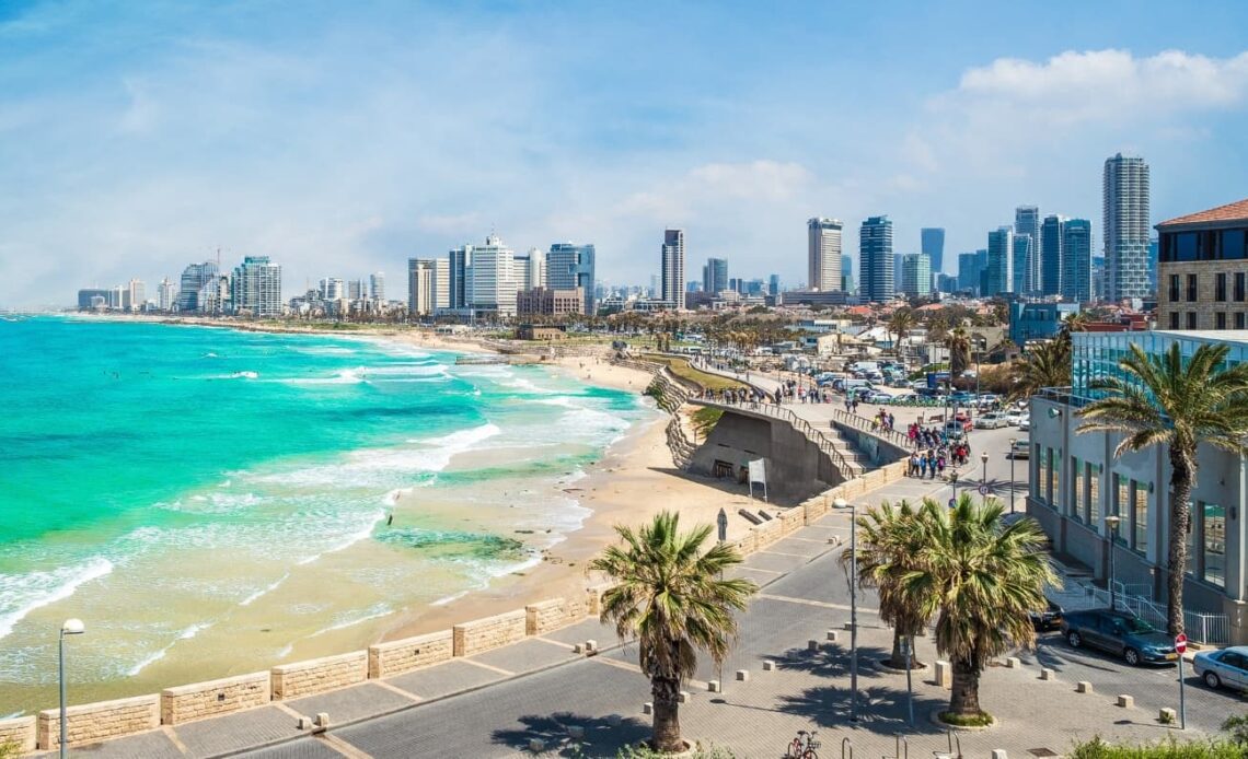 The city skyline in Tel Aviv, Israel, with a horseshoe-shaped beach, the azure blue ocean, and skyscrapers in the background