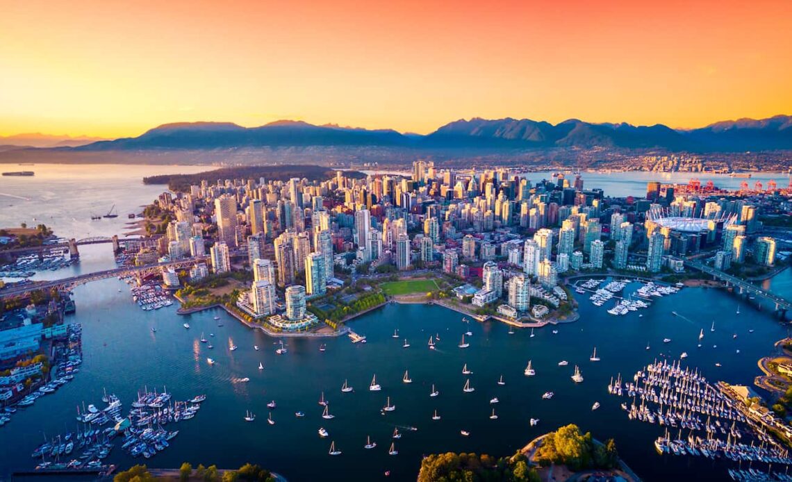 the stunning skyline of Vancouver, Canada as seen from above at sunset with mountains in the distance