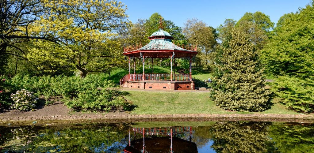 A gazebo in the middle of green trees and a river. 