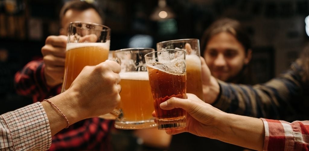 A four group of people toasting a glass of beer.
