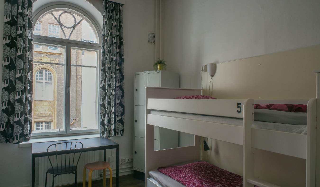 Dorm room at the Hostel Diana Park in Helsinki, Finland, with white bunk beds and curtains framing the windows as natural sunlight streams in