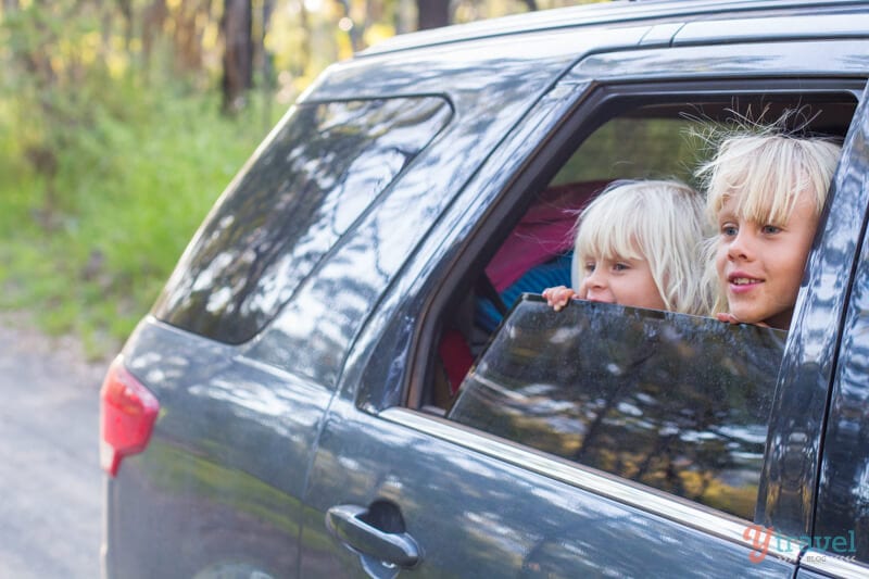 young girls sticking head out of car