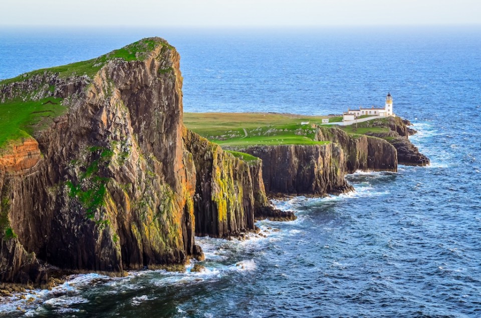 View of Neist Point lighthouse and rocky ocean coastline, highlands of Scotland