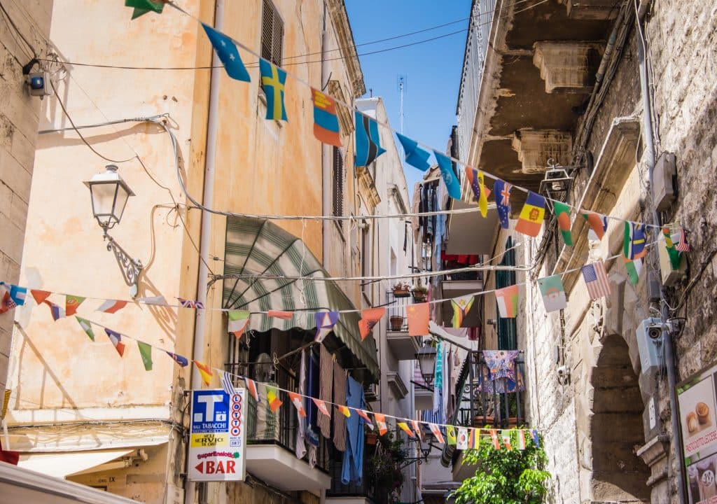 Old town streets in Bari, Italy, with colorful streamers hanging between the windows.