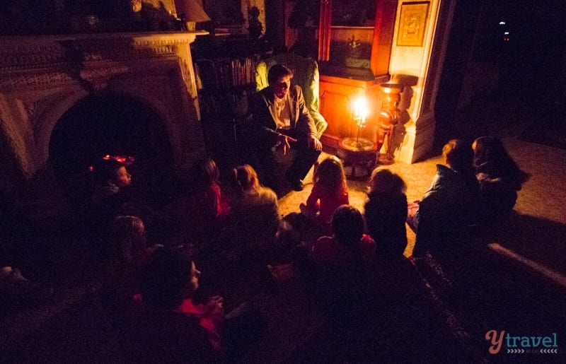 person telling ghost stories to chidlren under candlelight 