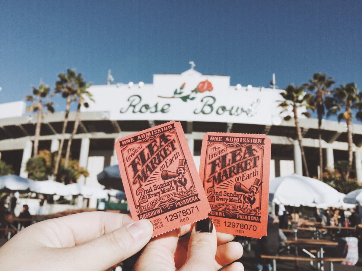 Two hands holding tickets in front of the Rose Bowl stadium to the Rose Bowl flea market in Los Angeles, California