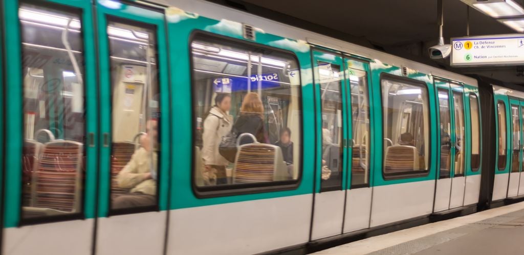 A green metro train stop to the train station.