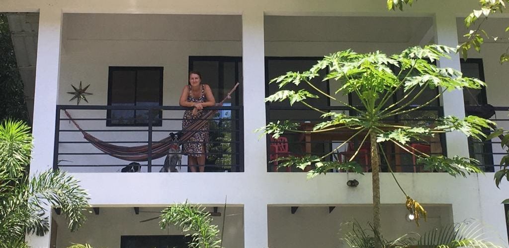 A woman standing in a two-story house with plants around.