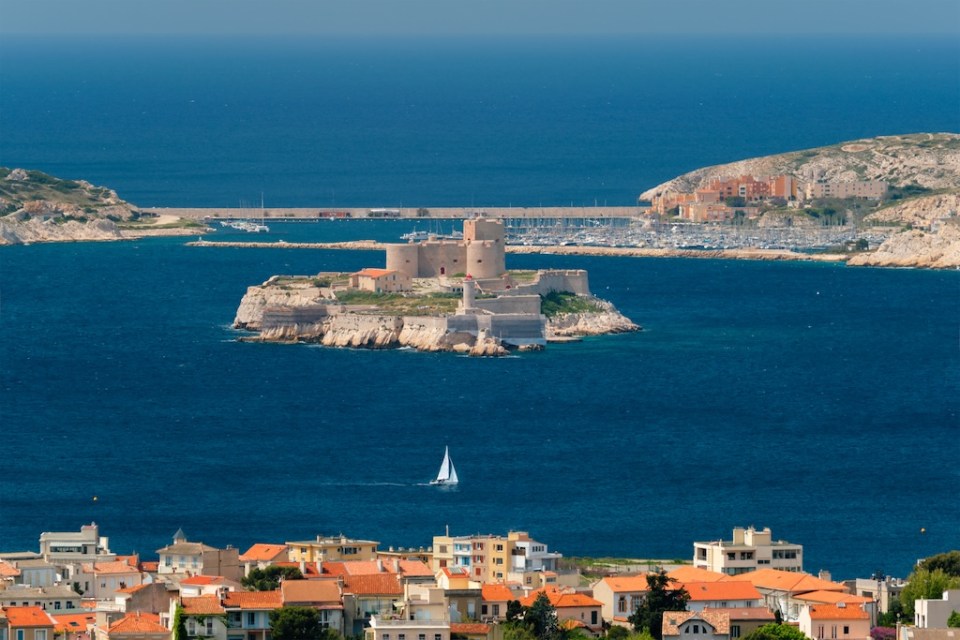 View of Marseille town and Chateau d'If castle famous historical fortress and prison on island in Marseille bay with yacht in sea. Marseille, France