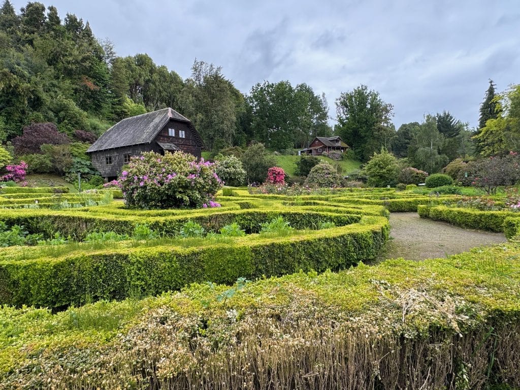 An outdoor museum with a traditional German wooden home surrounded by hedges and gardens.