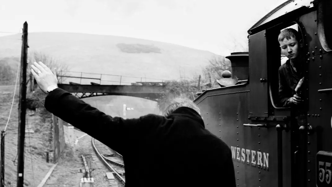 4 - A railway official signals to a worker aboard a steam train, a British invention first introduced in the early 1800s.