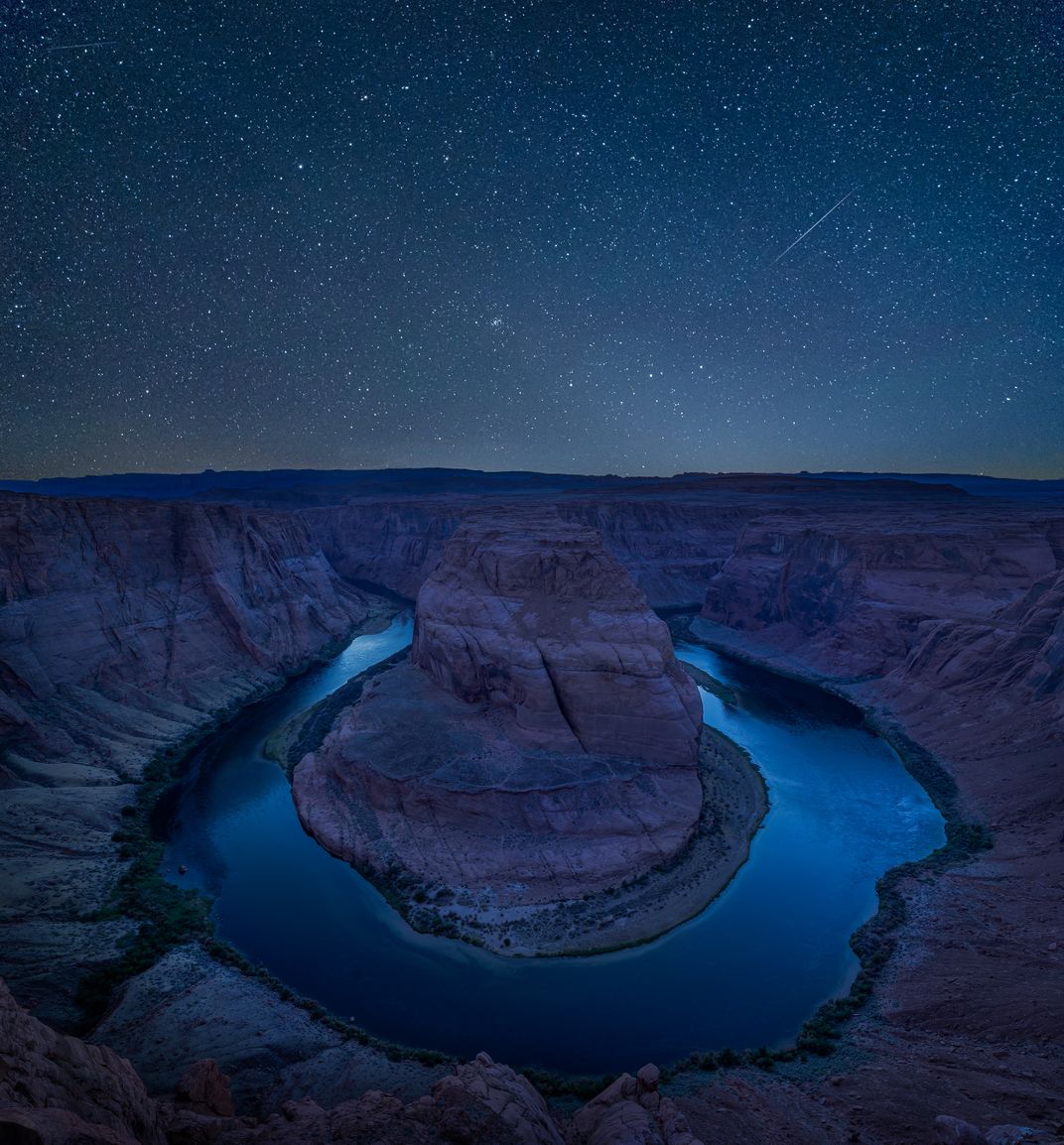 A starry night sky reflects light off the shallow waters of Horseshoe Bend in Glen Canyon National Recreation Area