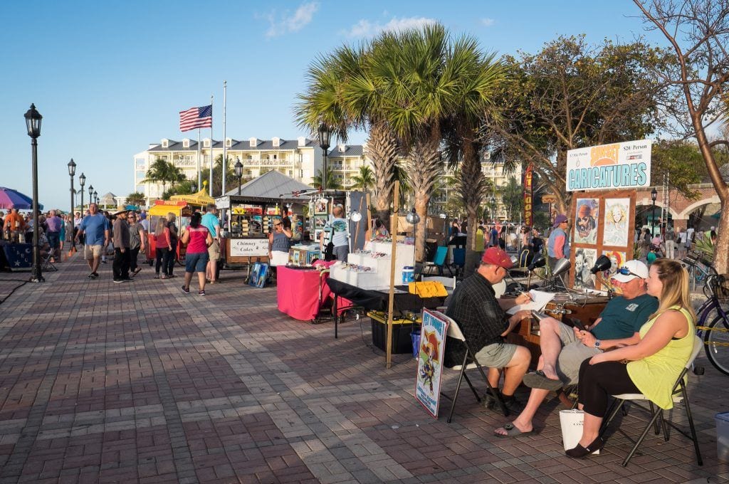 People gathering at outdoor booths for the sunset celebration on the edge of the water in Key West.
