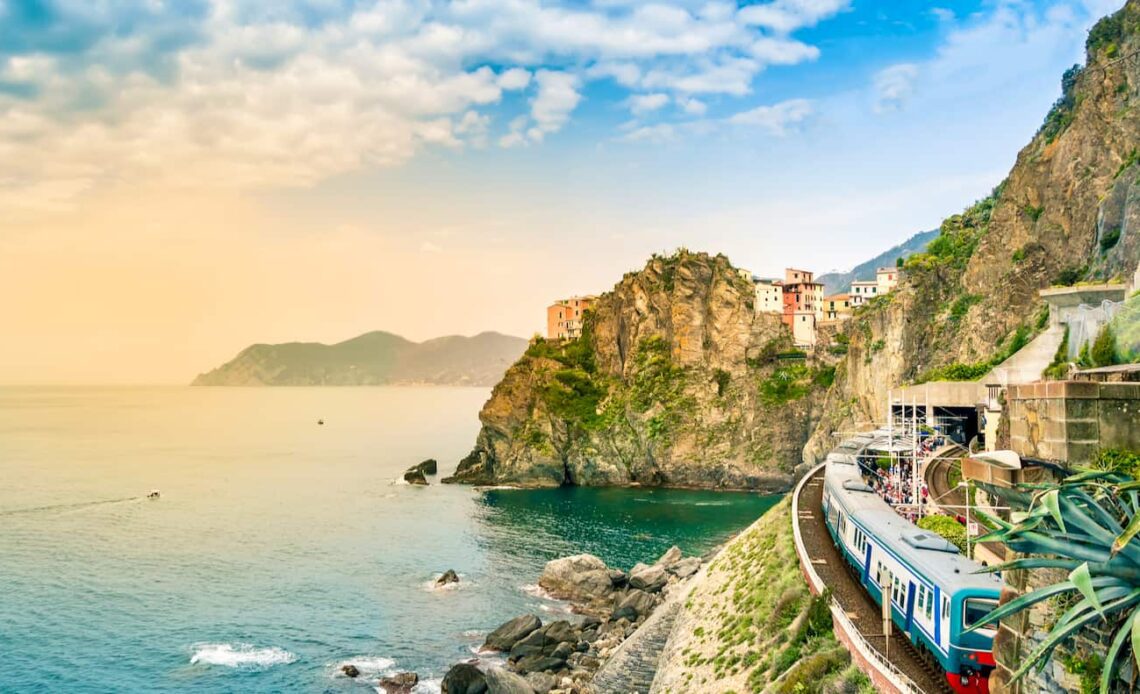 A train traveling along the rugged cliffside villages of Italy at sunset