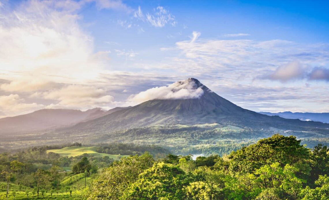 A sunny, bright day overlooking the towering Arenal volcano in Costa Rica with lush jungle in all directions