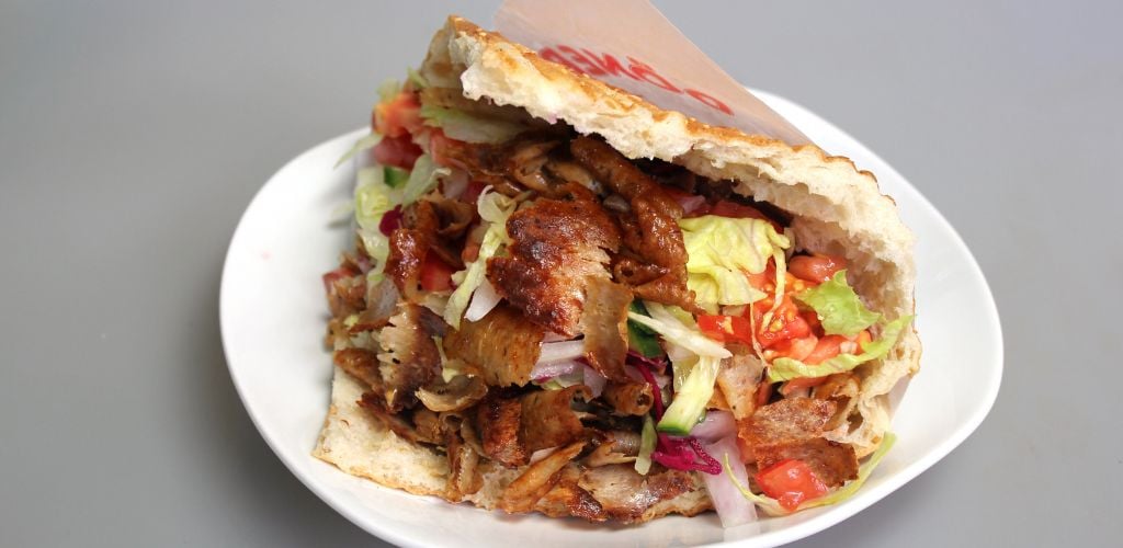 A plate of a mix of meat and vegetables in a pita.