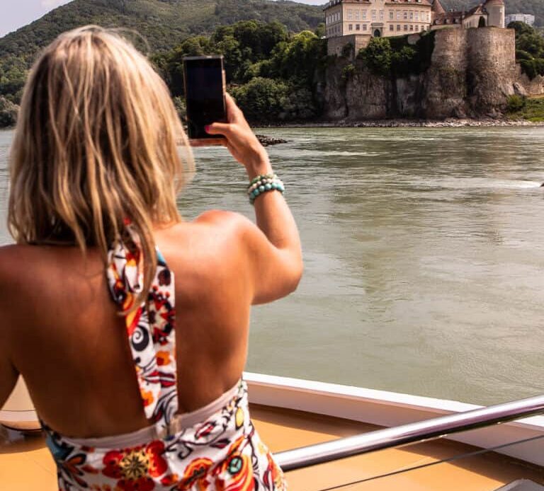 Lady taking photo of a castle from a river cruise ship in Austria